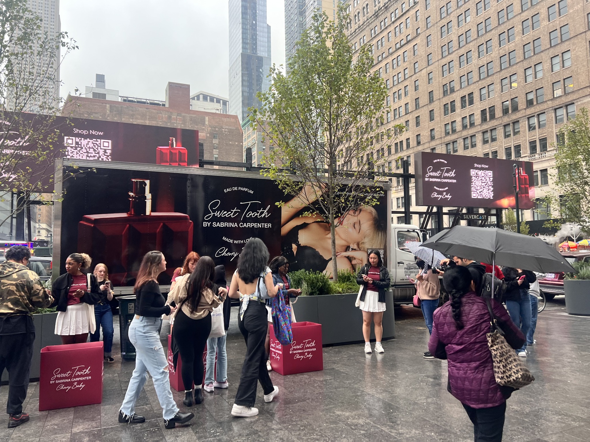 Cherry Baby campaign billboards and a branded truck with people gathered on a New York City street